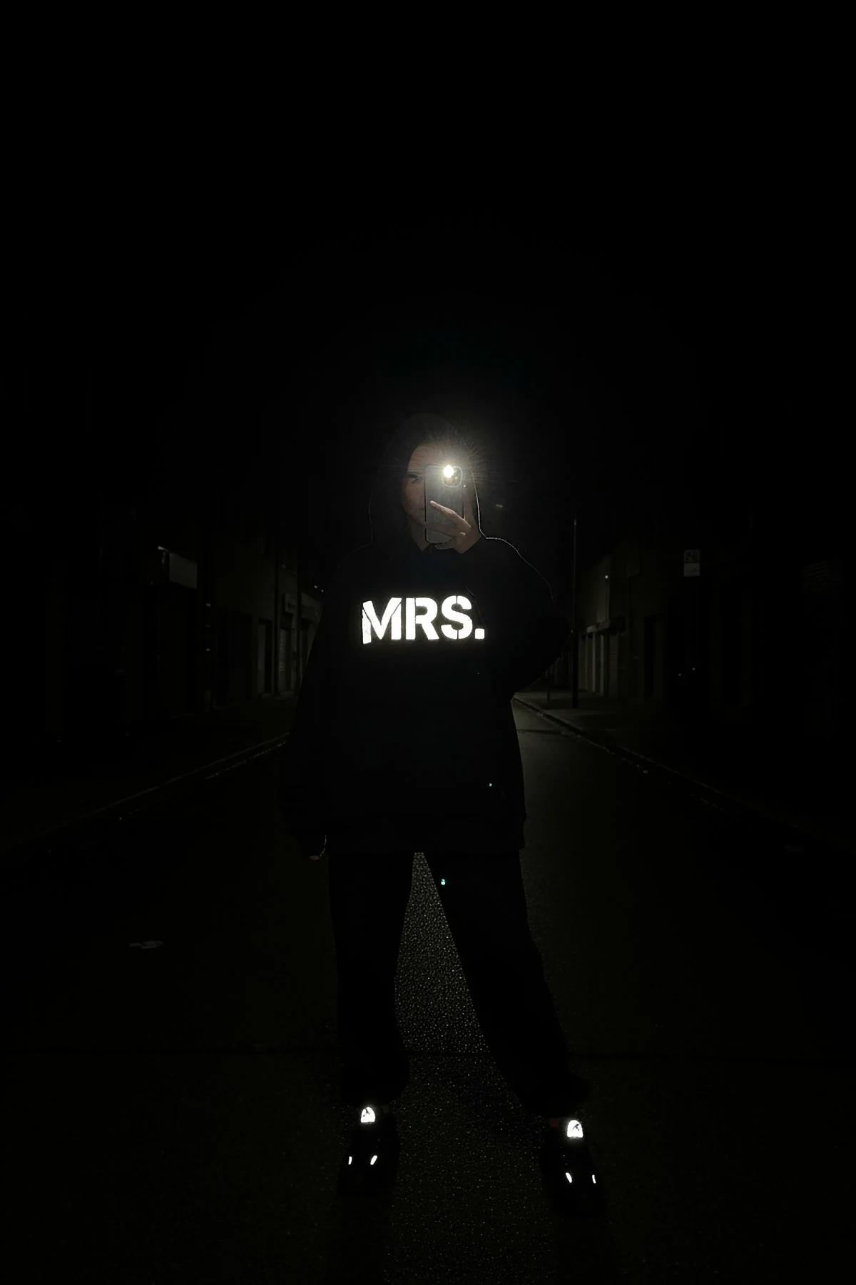 Reflective Mrs. Hoodie in black with glow-in-the-dark front print and illuminated shoes at night