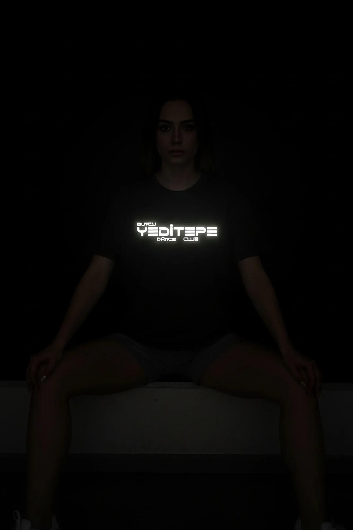 Black t-shirt with "Buğçu Yeditepe Dance Club" reflective graphic in the center, worn by a woman sitting.