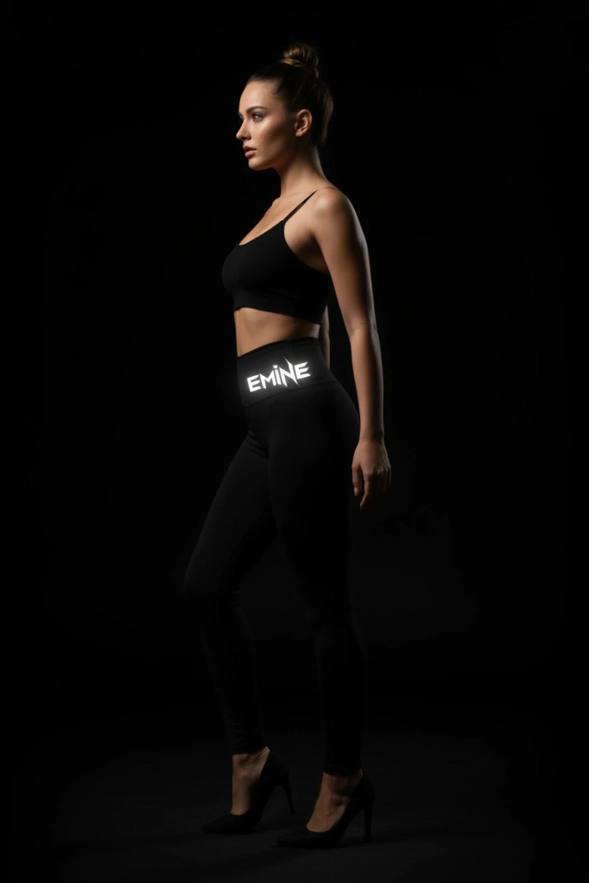 Reflective glow-in-the-dark black leggings with EMINE logo on waistband worn as part of a festival outfit
