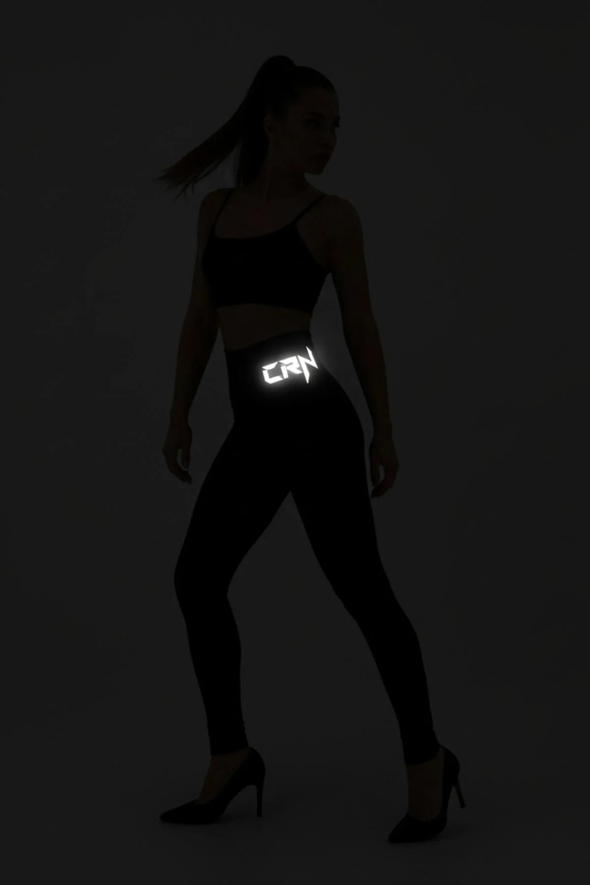 Glow-in-the-dark black leggings with illuminated logo at waistband in dark setting