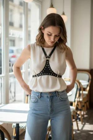 Siyah çivili vegan deri kadın omuz ve göğüs aksesuarı, beyaz crop top ile kombinlenmiş.
