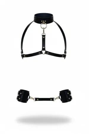 Black vegan leather body harness with adjustable straps and central O-ring, paired with detachable wrist cuffs.