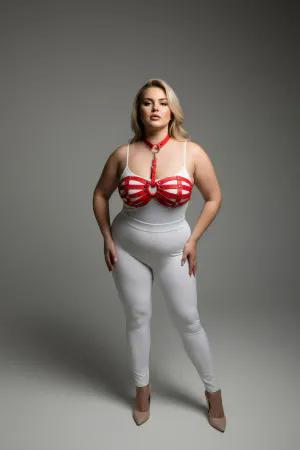 Red faux leather strappy chest harness with O-ring detail worn by a plus-size model