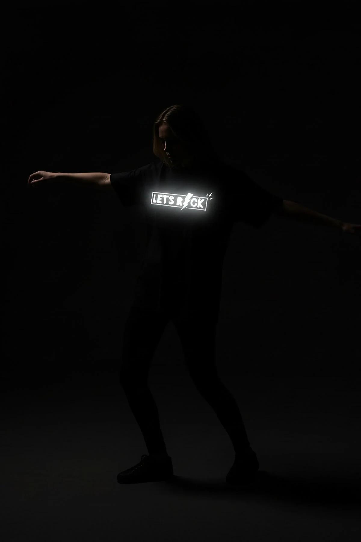 full-length view of relaxed-fit black reflective print t-shirt styled with dark high-waist trousers