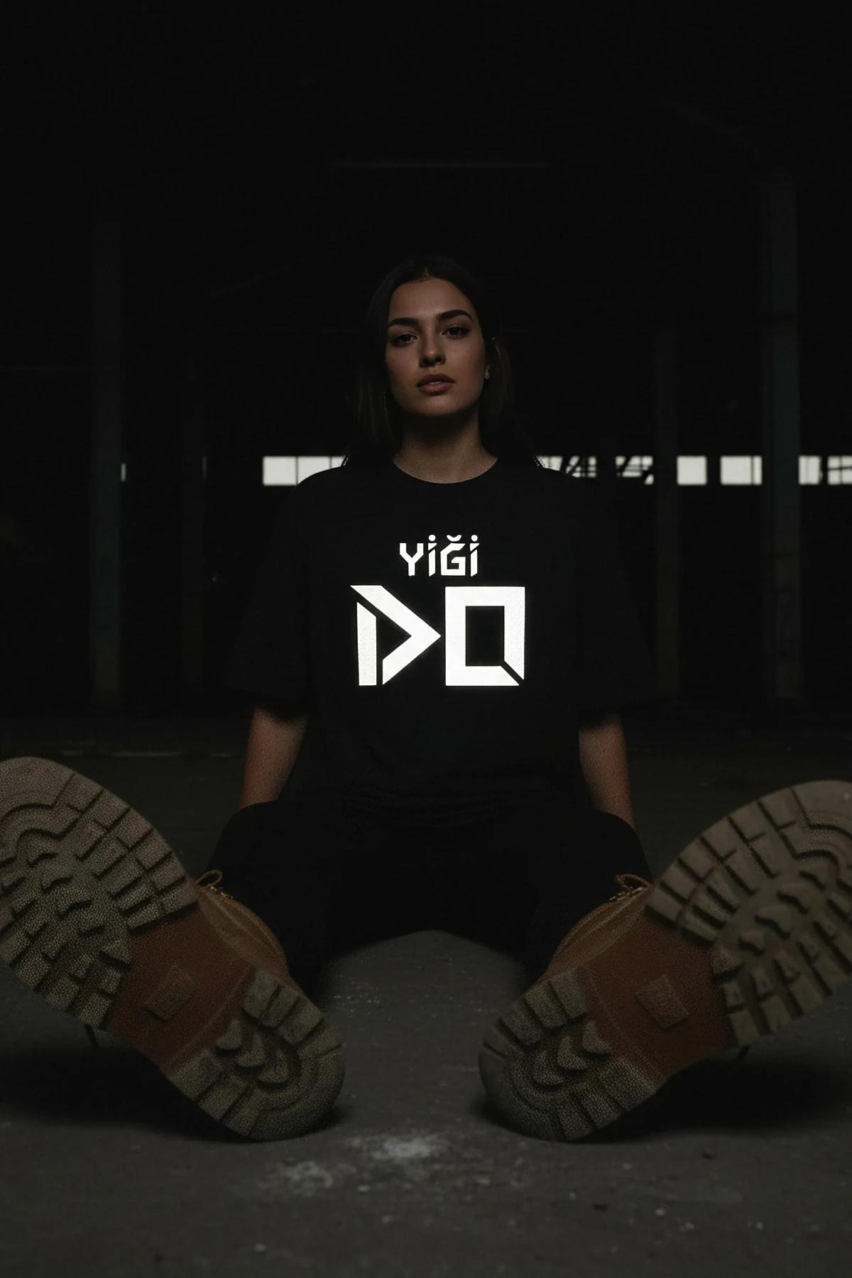 retroreflective print detail on black t-shirt showing geometric angular letterforms under direct light