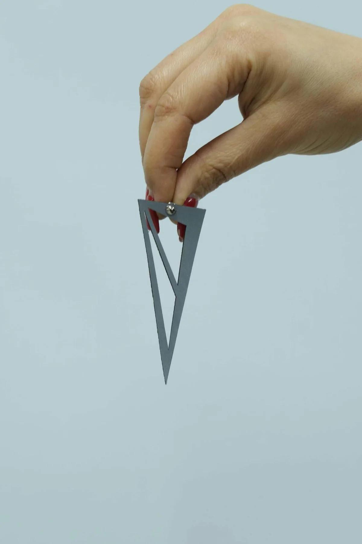 Gümüş metal üçgen küpe lazer kesim iç desen yakın çekim, parlak perdah detayı