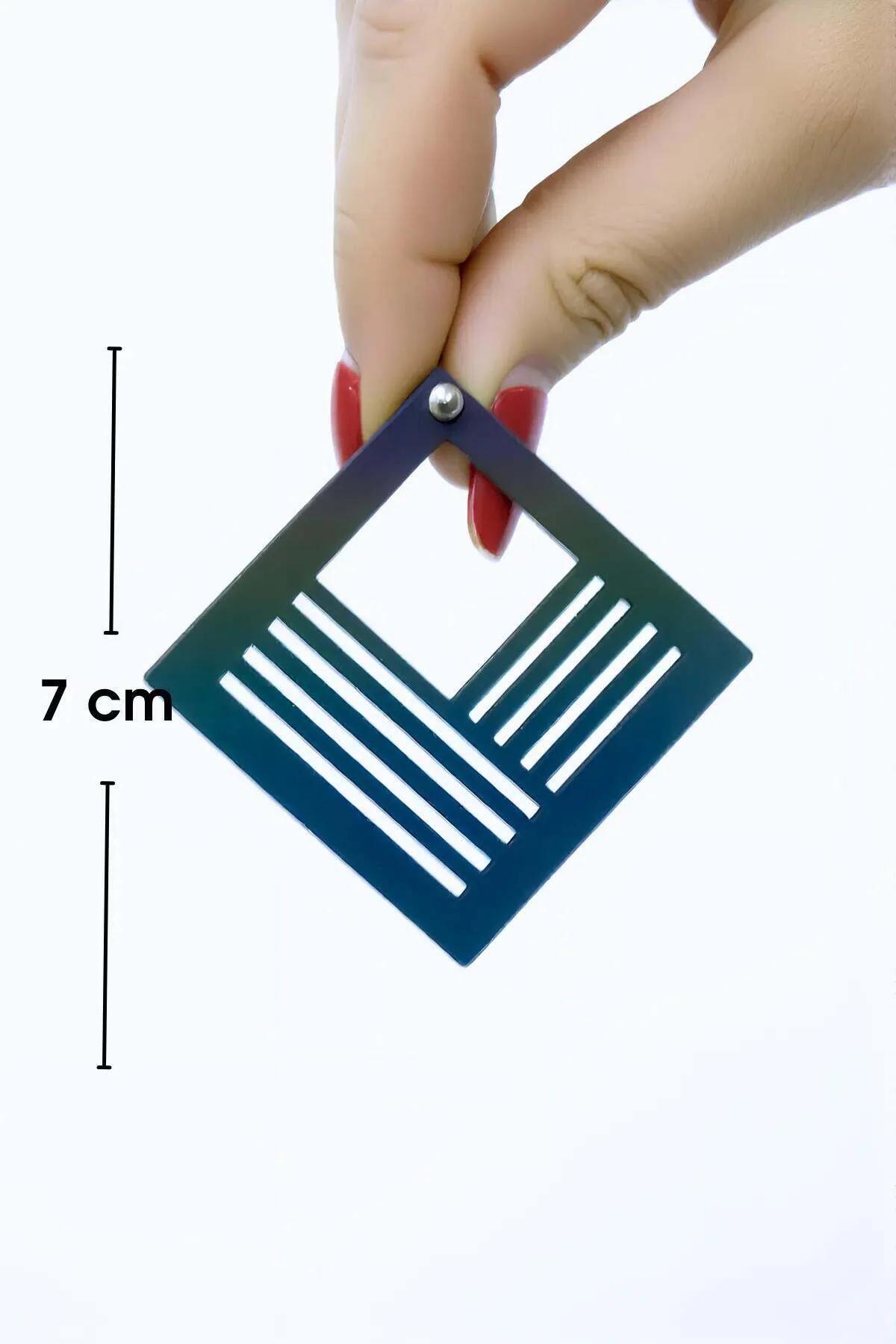 Close-up of gold-tone square earring showing precision cutout line pattern and polished reflective surface