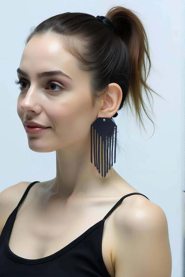 Black faux leather geometric shield earring with laser-cut vertical fringe strips worn on model with high ponytail