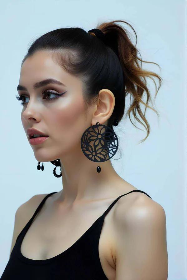 Black faux leather floral laser-cut circular disc drop earrings with small bead pendant worn on model