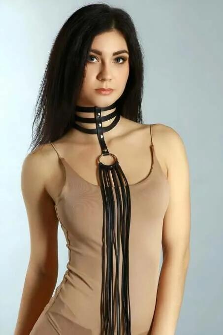 Close-up of black faux leather choker straps and gold-tone O-ring hardware detail