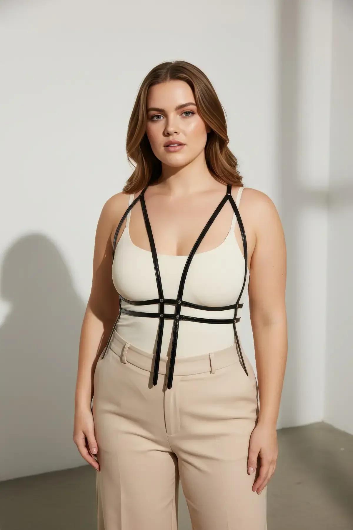 black geometric cage harness layered over white tank top with beige wide-leg trousers