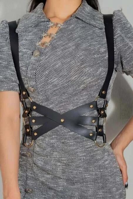 close-up of gold-tone dome studs and O-ring hardware on black PU leather harness panels