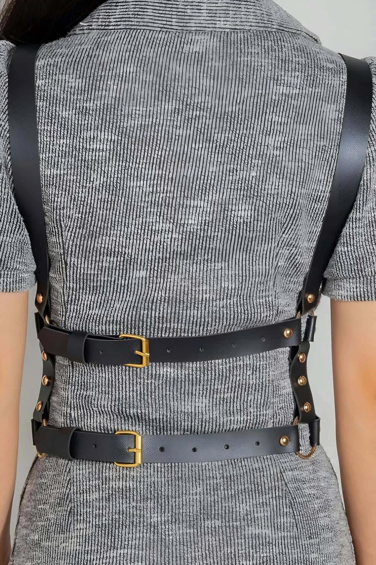 shoulder strap and decorative chain detail of black cross-back harness layered over dress