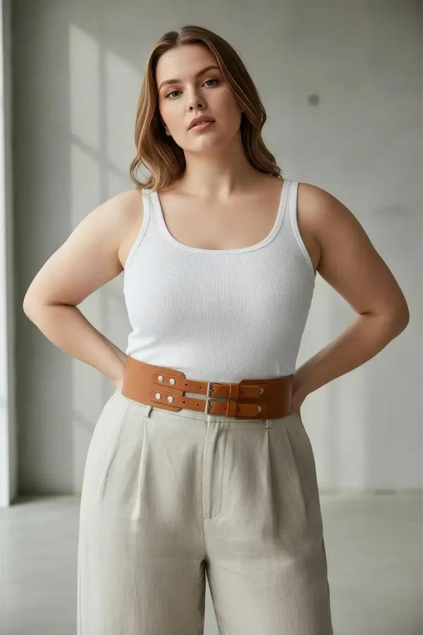 wide tan faux leather corset belt with double silver buckles worn over white tank and linen trousers