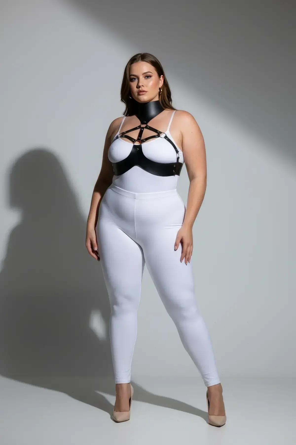 black faux leather chest harness with structured high collar and silver O-rings worn over white bodysuit
