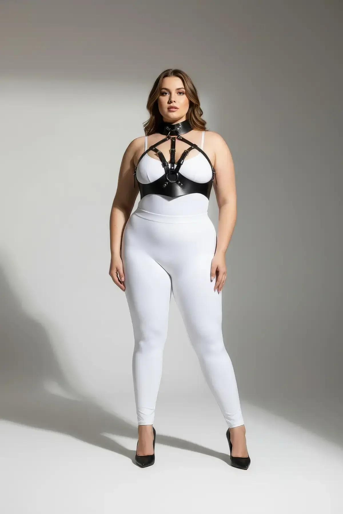 Black faux leather body harness with high choker collar and silver O-ring, worn over white bra and leggings, plus-size model