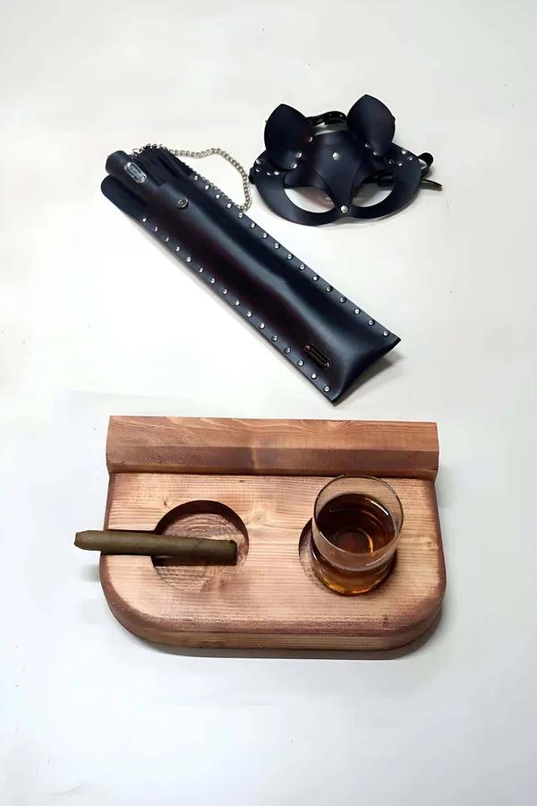 black faux leather cat ear mask and studded handle whip set with silver chain accent laid flat on white surface