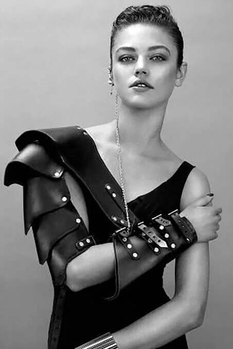 Close-up of black faux leather arm cuff with three silver pin-buckle straps and dome stud hardware detail