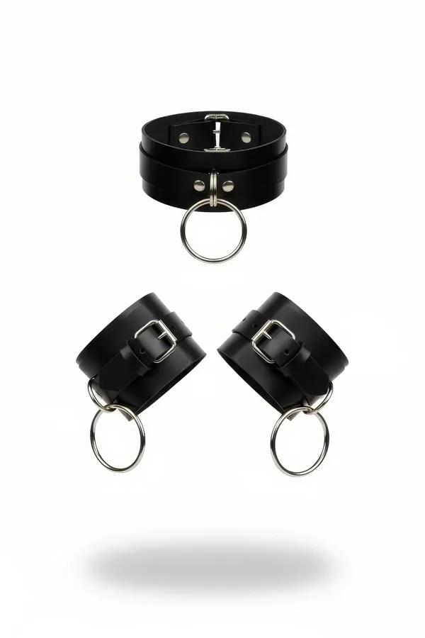 Black faux leather choker and wrist cuffs set with silver O-rings and roller buckle closures on white background