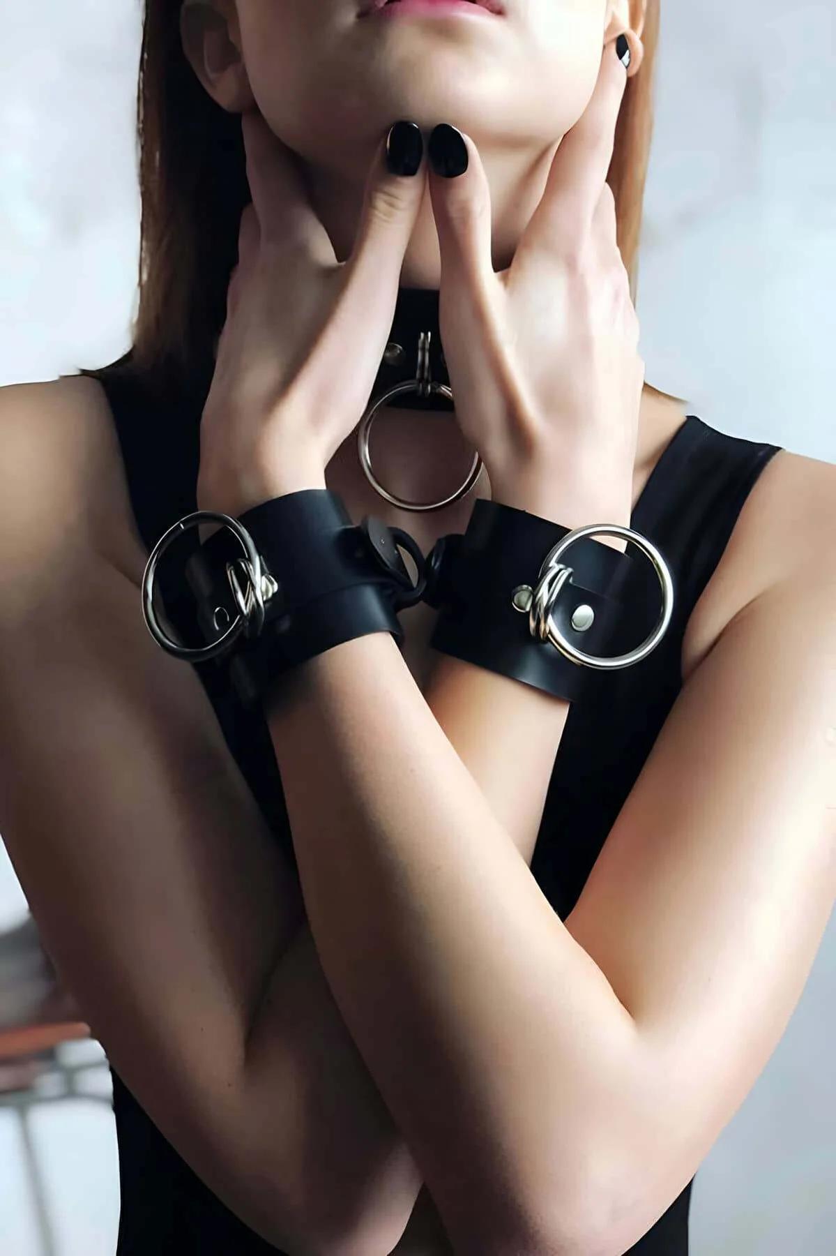 Close-up of black faux leather choker with large gold O-ring on female model neck