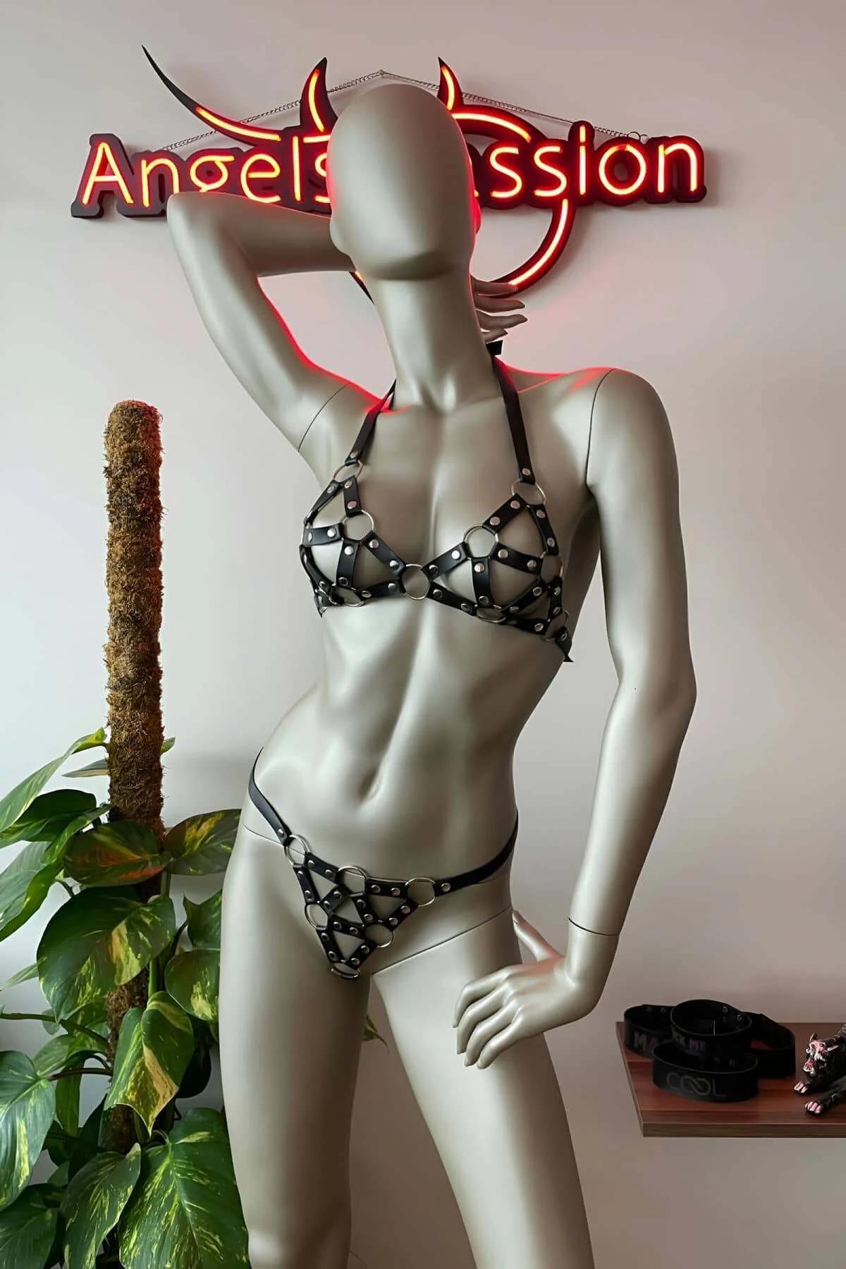 Black faux leather studded bra and thong harness set with silver O-rings and rivet details on mannequin