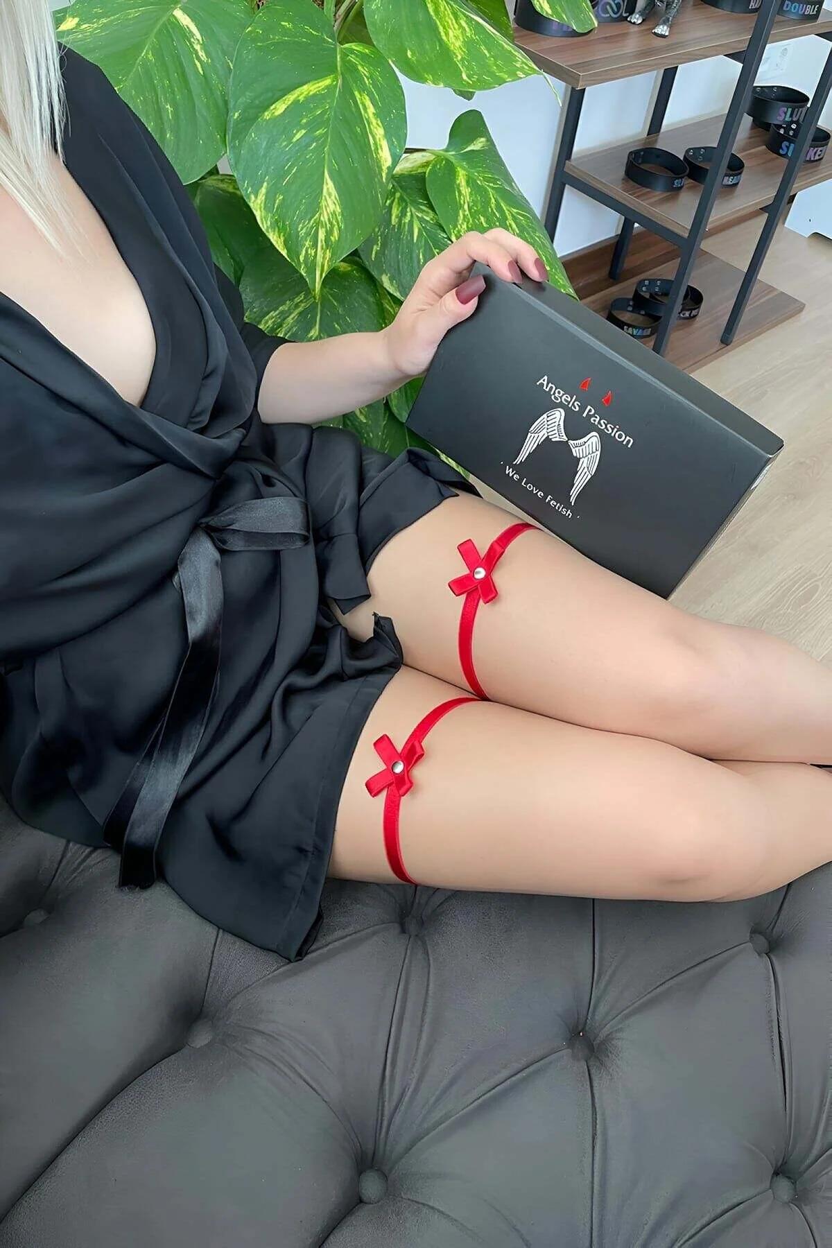 Close-up of red satin bow with single faux-pearl bead on thigh garter band