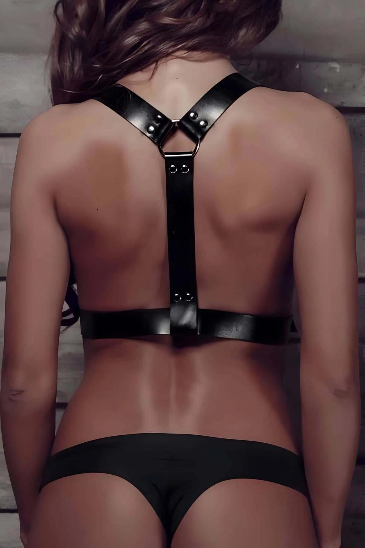 Close-up of silver D-ring shoulder connection on black faux leather chest harness