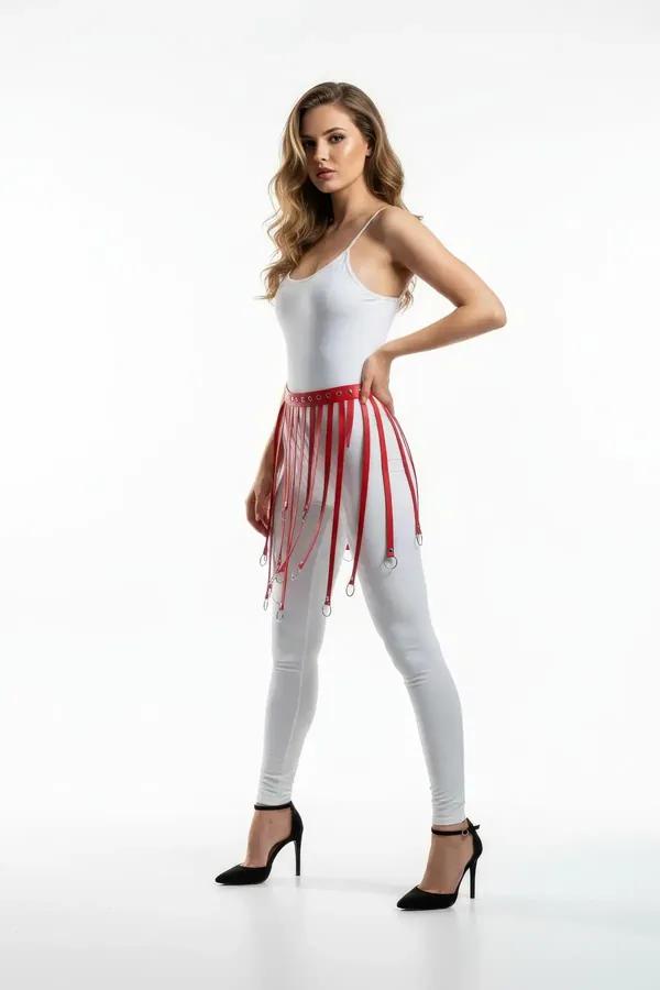 Red faux leather waist harness with vertical fringe strips and silver O-ring tips worn over white leggings