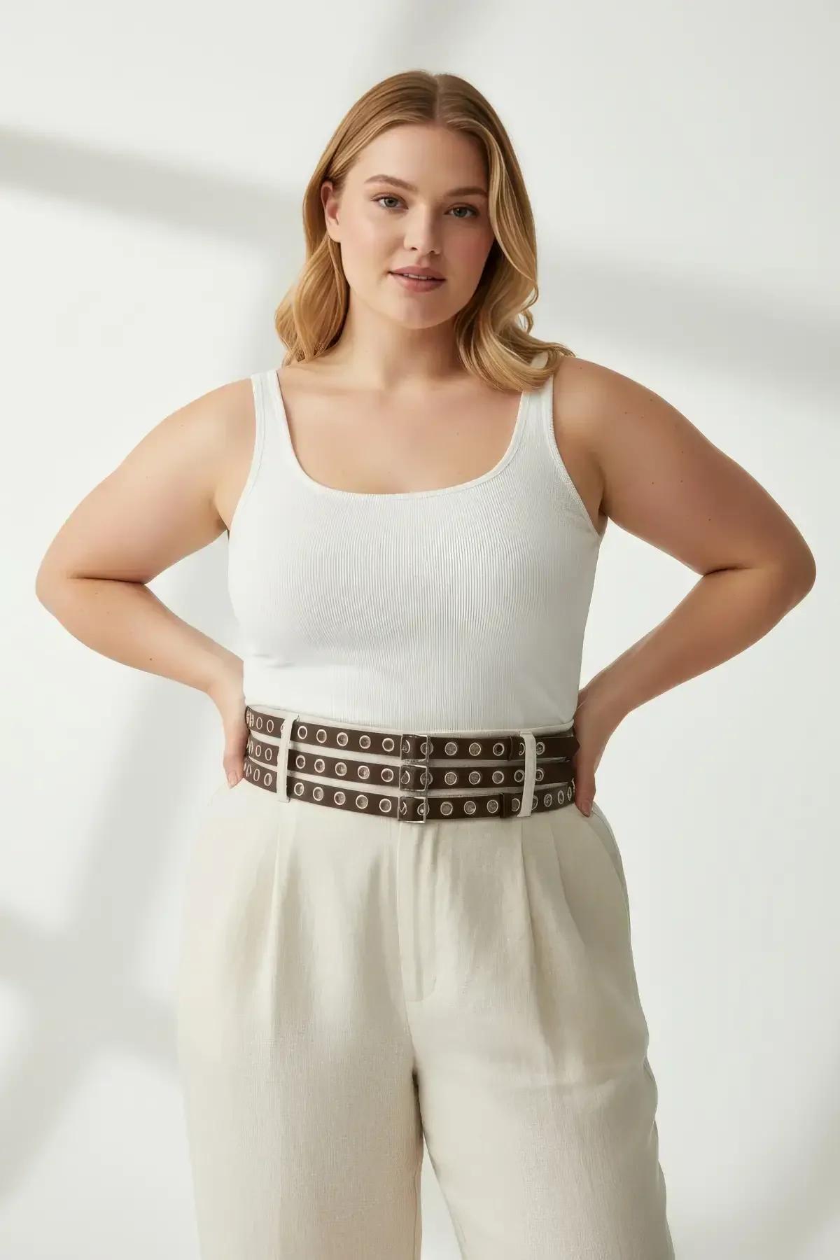 dark brown three-strap harness belt fastened over high-waist wide-leg trousers showing full stack of eyelet rows