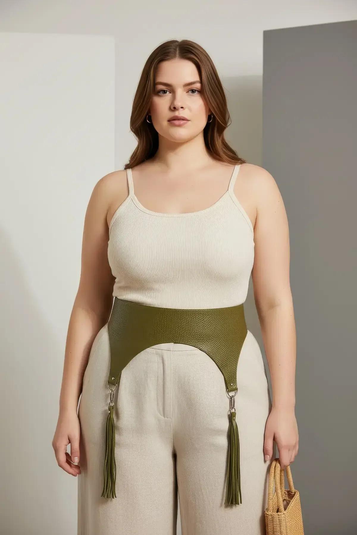 high-waisted olive harness with tassel garters styled over wide-leg beige trousers and white tank top