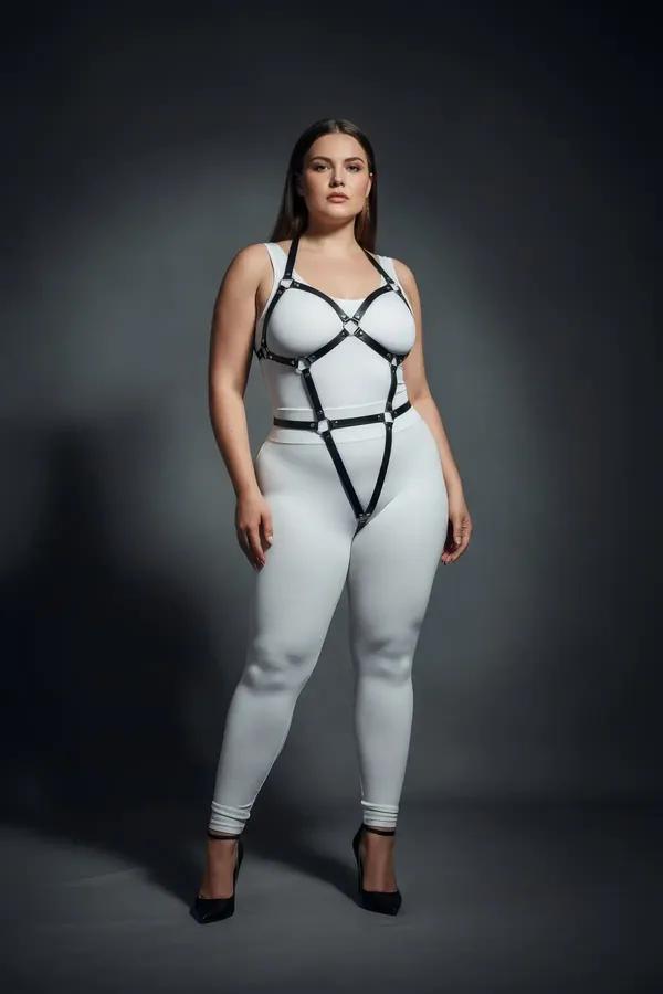 Black vegan leather full body harness with silver O-rings, wide chest frame and leg straps, worn on plus-size model