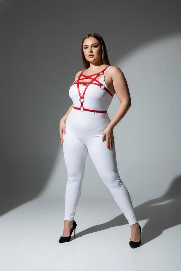 Red vegan leather starburst chest harness with silver O-rings worn over white bodysuit, plus-size model