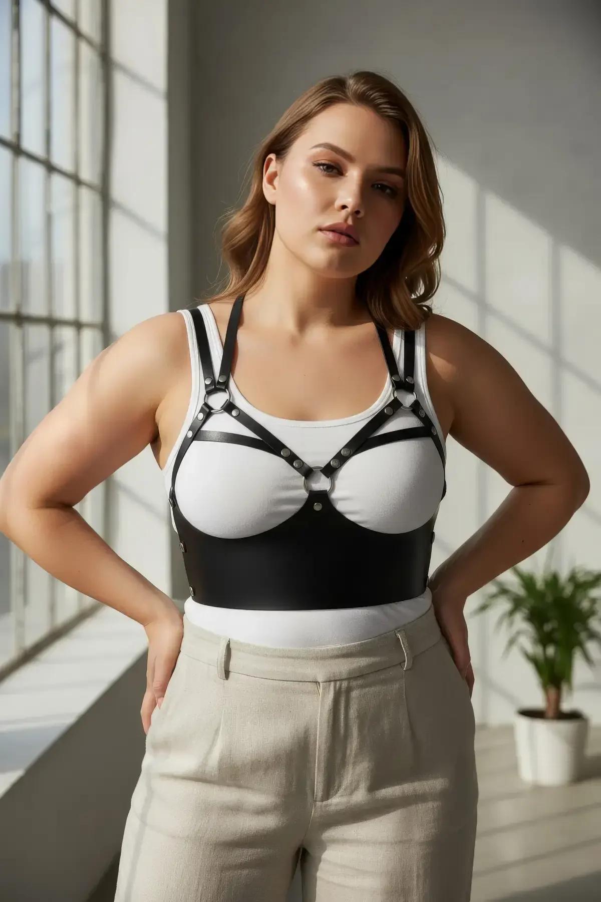 Close-up of silver stud details on black faux leather harness straps against white ribbed top