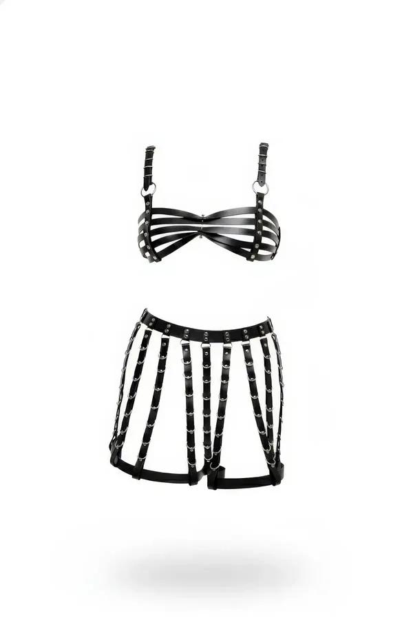 Black faux leather strappy cage bra and open-panel harness skirt set with silver O-rings on white background
