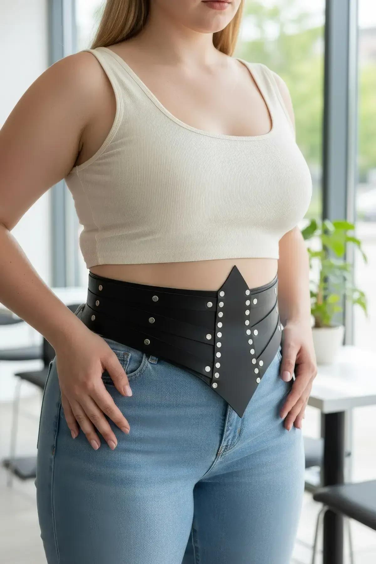 front detail of black faux leather waist corset showing five rows of silver dome studs and grommet eyelets