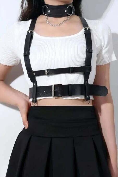 Close-up of silver pin-buckle adjuster on black PU leather shoulder strap of underbust harness