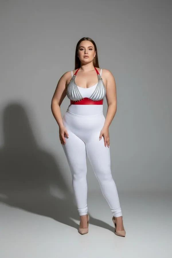 red faux leather chest harness with silver chain straps worn by plus-size model over white high-waist leggings