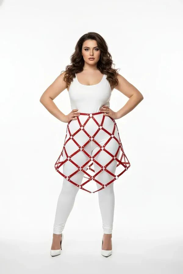 Red faux leather lattice skirt harness with gold O-rings worn over white leggings and bodysuit, mid-thigh length cage structu
