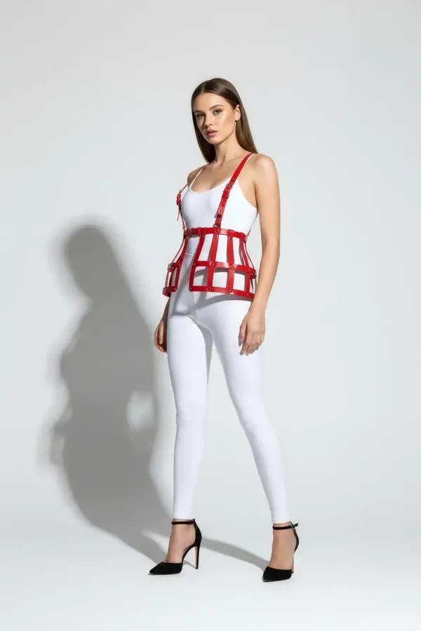 Red faux leather cage waist harness with open grid strap structure and silver rivets worn over white fitted top