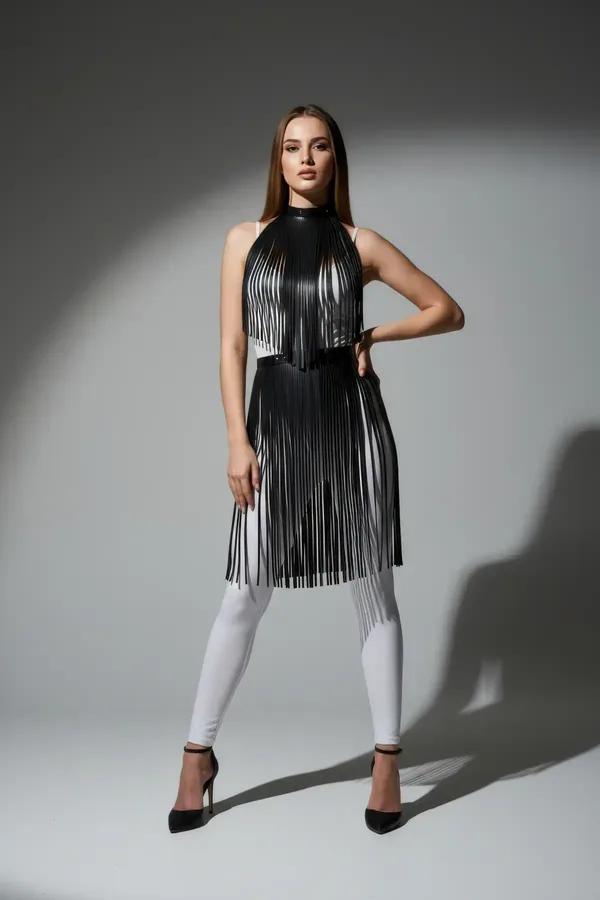 black faux leather fringe mock neck overlay with two-tier fringe panels worn over white leggings