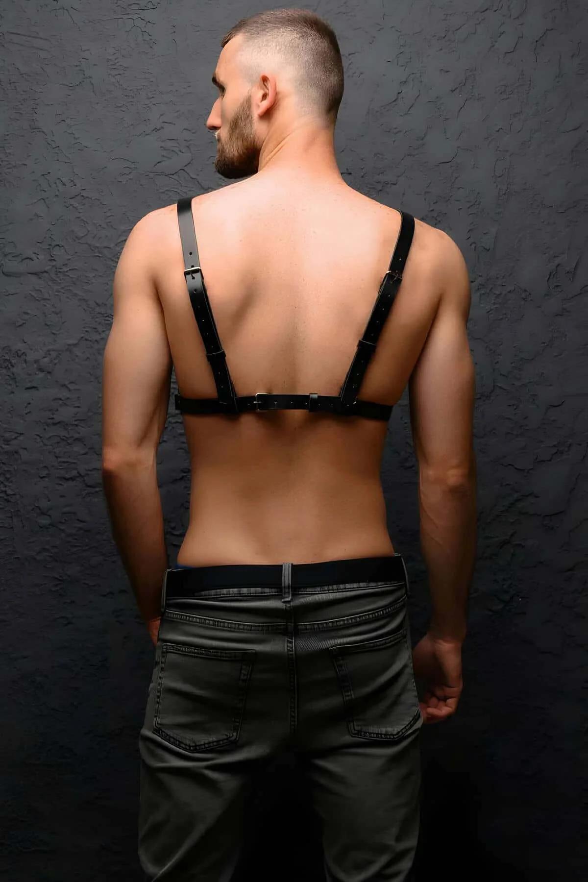 close-up of silver O-ring and stud rivets on black faux leather chest harness strap junction