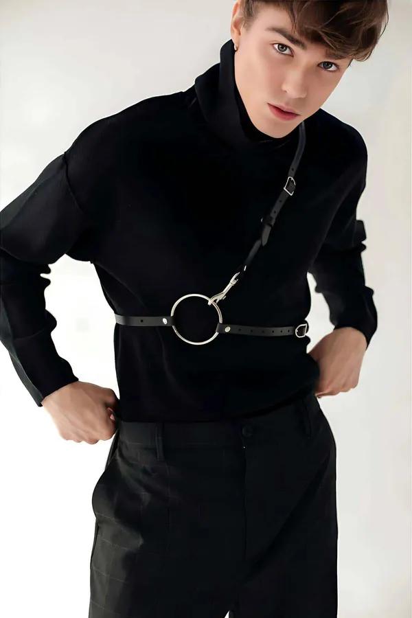 Black faux leather adjustable O-ring body harness with silver lobster clasp and diagonal shoulder strap worn over black turtl
