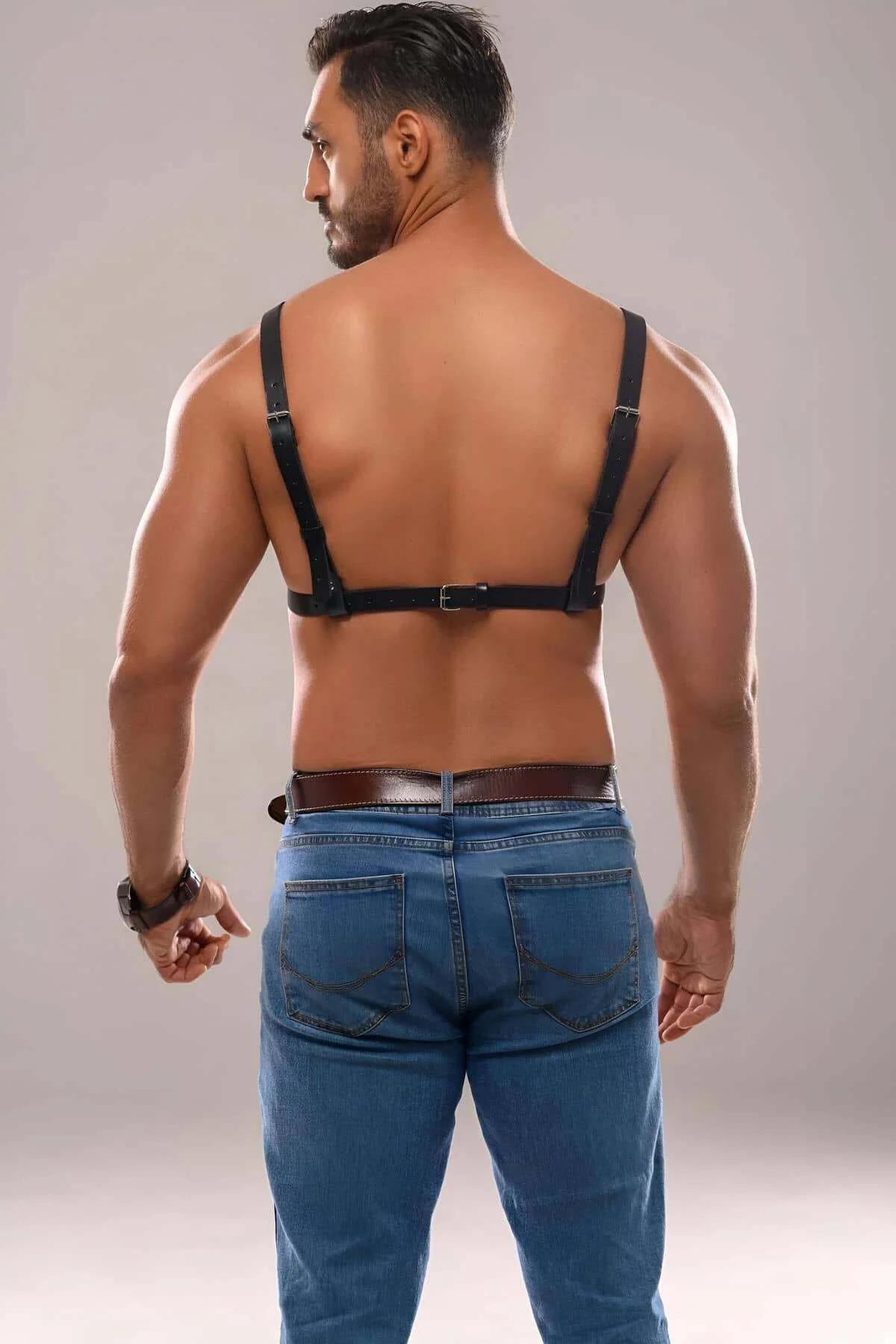 Close-up of silver O-ring junction on black men's chest harness showing strap width and metal hardware