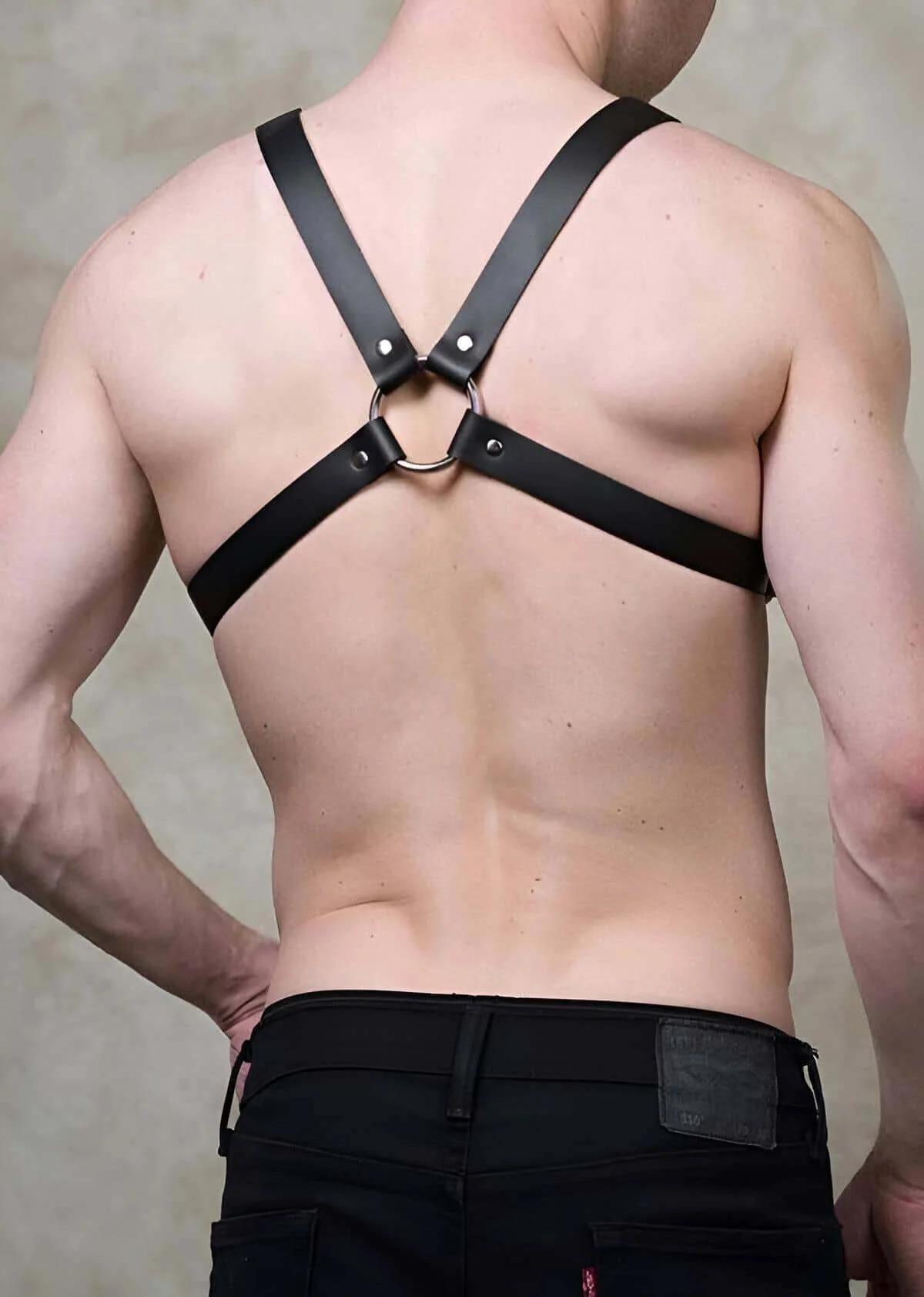 Adjustable black faux leather chest harness close-up showing silver-tone buckle detail on shoulder strap