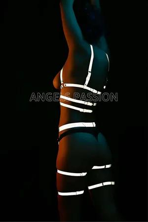 Reflective full body harness and garter set on a model, white reflective straps against black.
