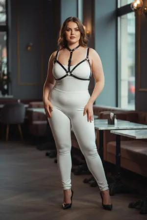 Black faux leather strappy body harness worn by a plus-size model, showing adjustable straps and O-ring detail.