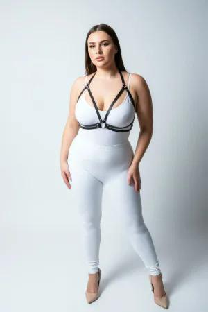Black minimalist faux leather chest harness with central O-ring and adjustable straps worn by a plus-size model.