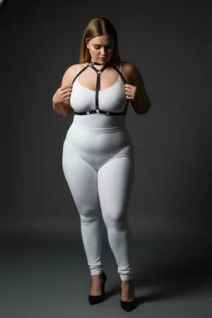 Black faux leather strappy body harness with silver O-rings and adjustable straps worn by a plus-size model.