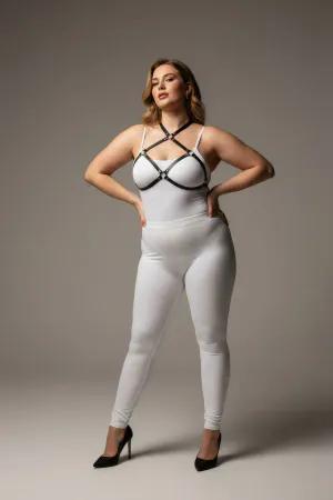 Black faux leather strappy chest harness with O-ring details, worn by a plus-size model.