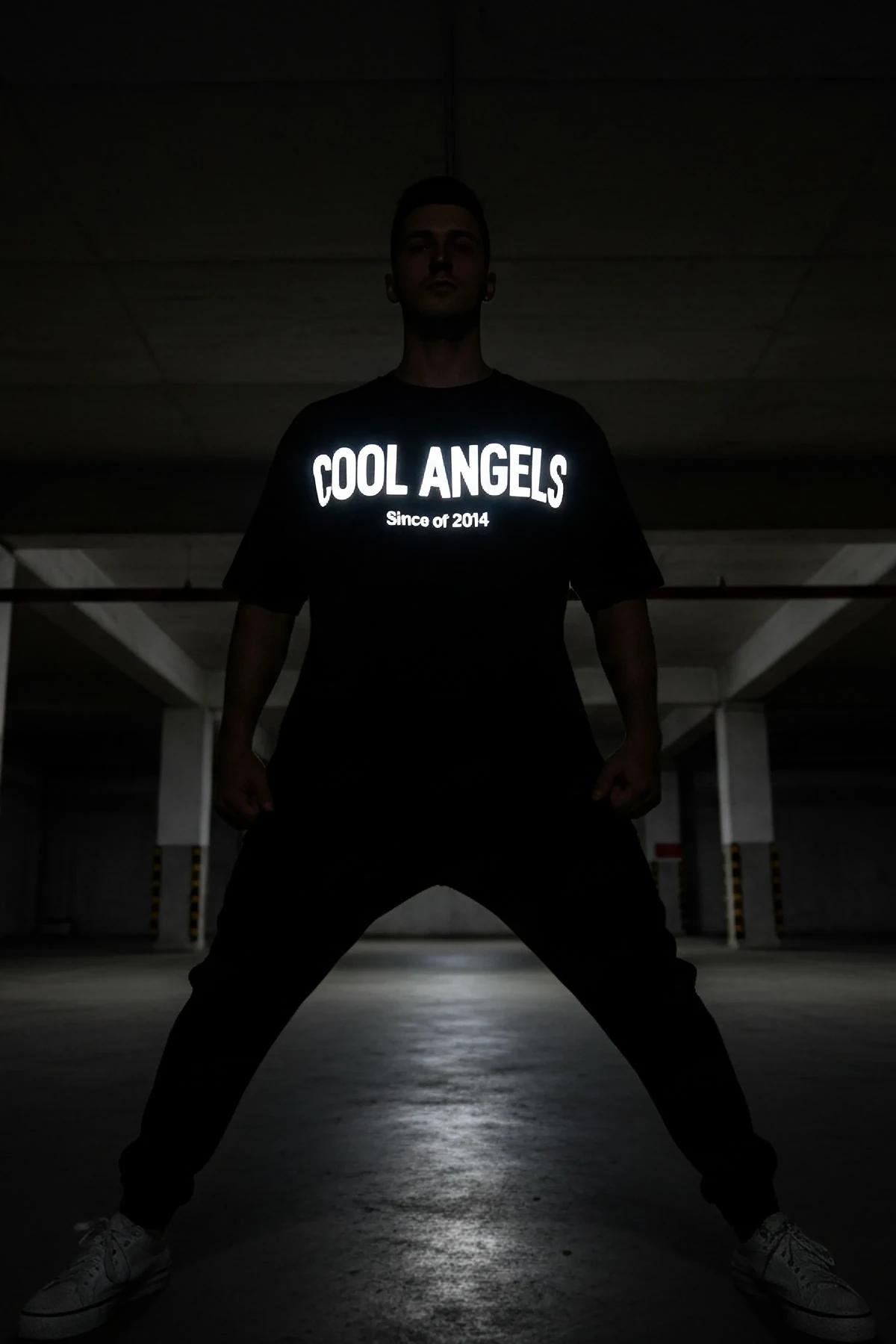 black oversized glow-in-the-dark reflective t-shirt with bold COOL ANGELS Since of 2014 chest graphic lit in low light